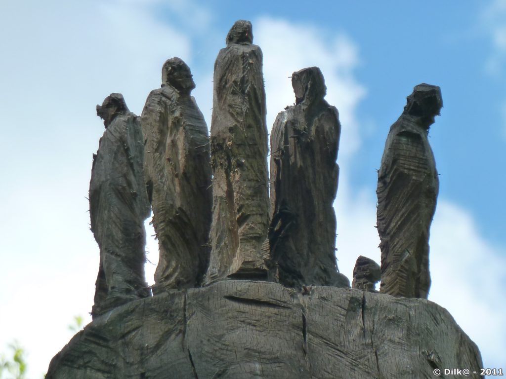 Silhouettes humaines en haut de la sculpture de bois nommée « Humanité »