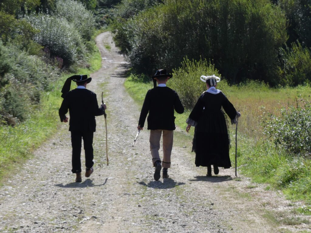 Trois personnes en costume breton qui vont au pardon de Sainte Anne via le GR34