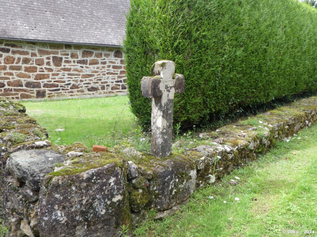 Petite croix sur un muret au milieu d'un village